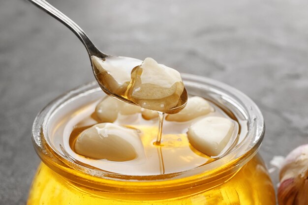 Spoon over glass jar with honey and garlic closeup