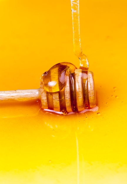 A spoon for honey together with high-quality bee honey, an old table on which there is a healthy and sweet bee honey and a homemade wooden spoon that allows you to transfer and pour honey