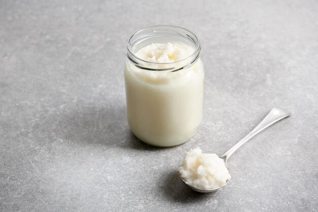 Spoon and jar with coconut oil on table