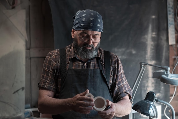 Мастер ложки в своей мастерской с деревянными изделиями и инструментами. Фото высокого качества