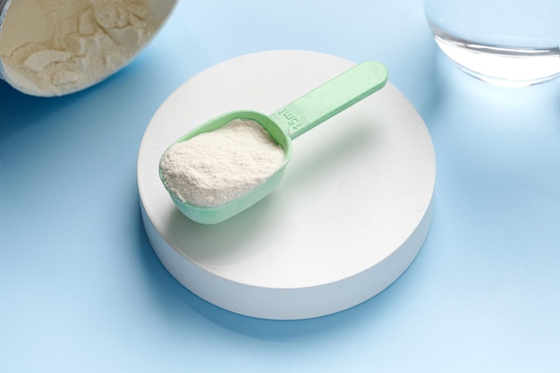 Spoon of natural lemon collagen protein powder on podium and blue background skin care copy space