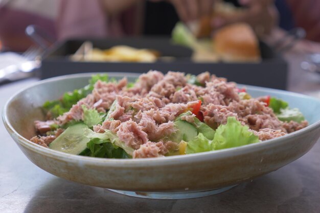 Spoon pick tuna salad from a bowl on table