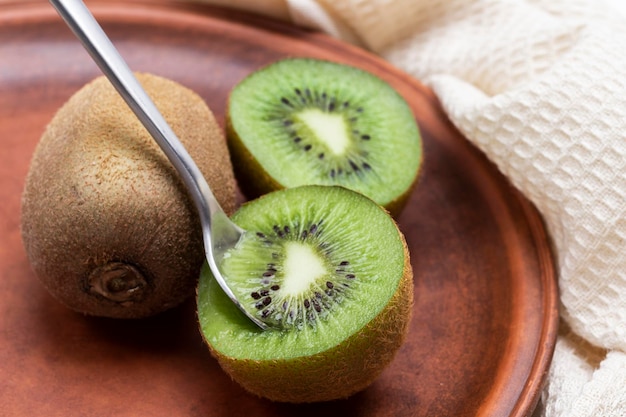 Spoon in pulp of the kiwi fruit Kiwi fruits on ceramic plate Top view White background