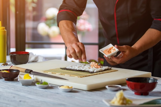 Spoon puts sauce on rice. Man's hand holds a spoon. High-calorie sauce for sushi. Filling for hosomaki rolls.