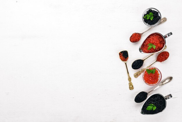 Spoon with black and red caviar on a wooden background Top view Free space for text