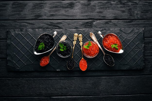 Spoon with black and red caviar on a wooden background Top view Free space for text