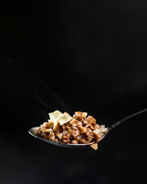 Spoon with boiled buckwheat on a dark background