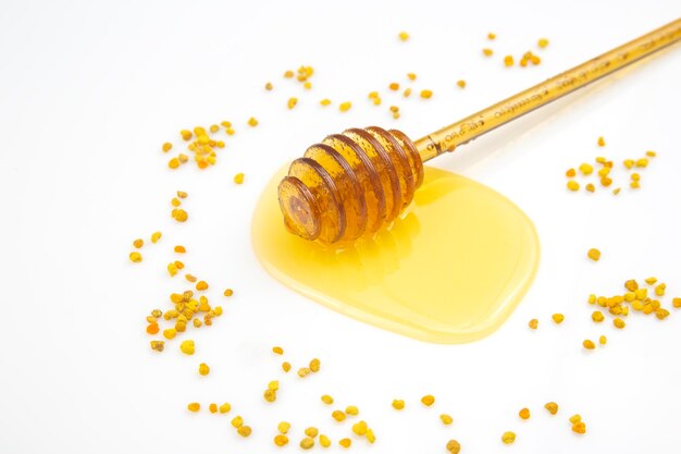 Spoon with fresh honey and pollen spilled on a white background. organic vitamin food