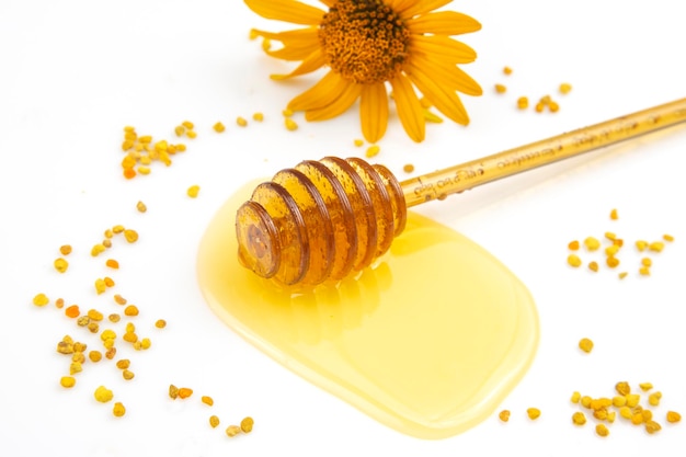 Ложка со свежим медом и пыльцой, пролитой на белом фоне, органическая витаминная пища