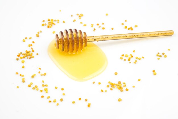 Spoon with fresh honey and pollen spilled on a white background organic vitamin food