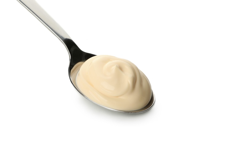 Photo spoon with mayonnaise sauce isolated on white background