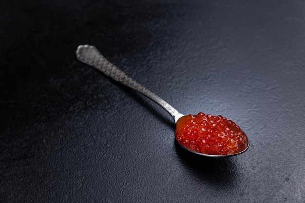 A spoon with red caviar on it