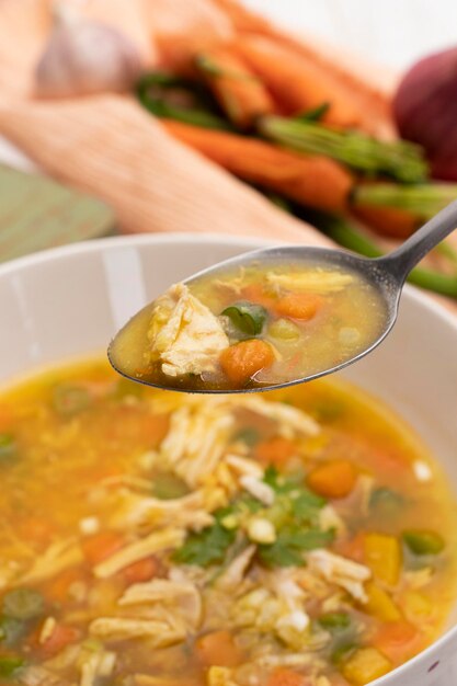 Photo spoon with shredded chicken soup and vegetables