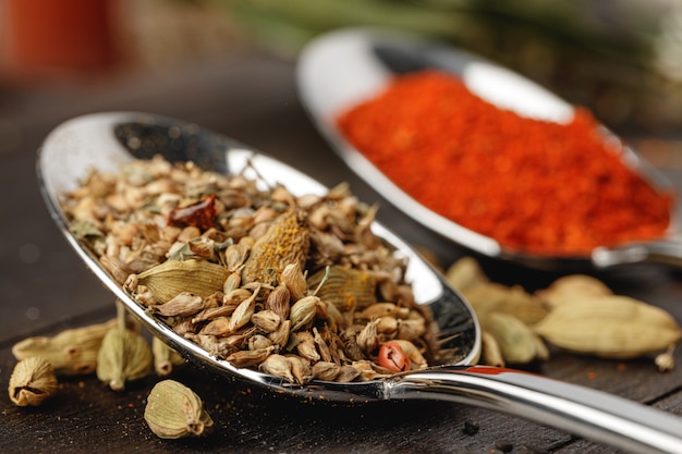 Spoon with spices on dark wooden table close up