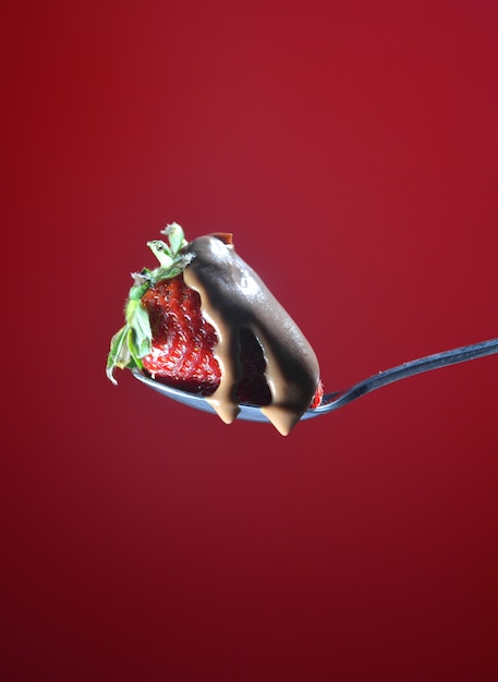 Spoon with strawberry, falling a little chocolate liquid