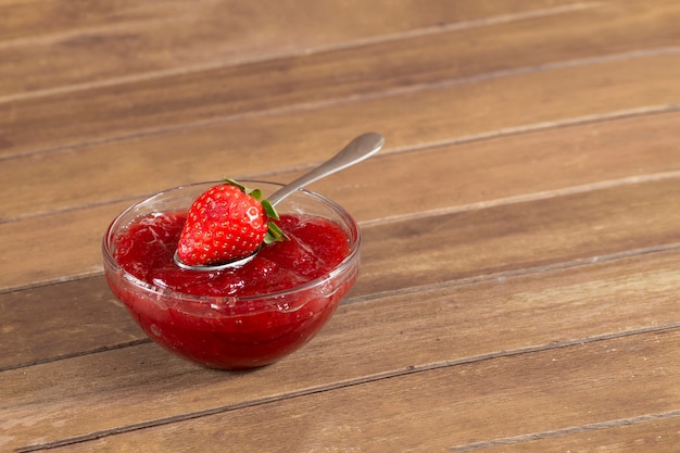 Spoon with a strawberry next to jam