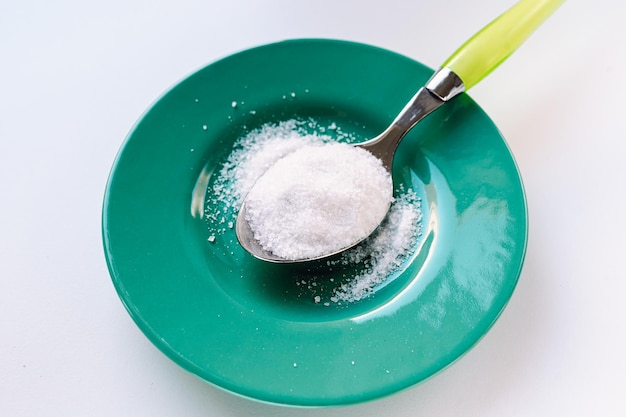 Spoon with sugar or sweetener on saucer side view