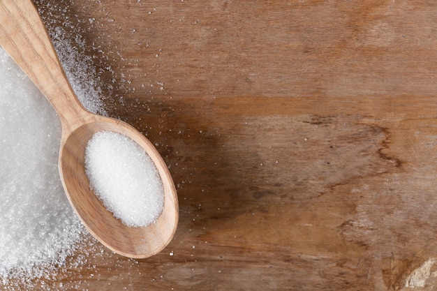 Spoon with sugar on wooden table