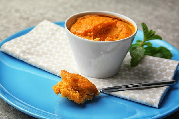 Ложка с вкусным морковным суфле и рамекин на тарелке крупным планом