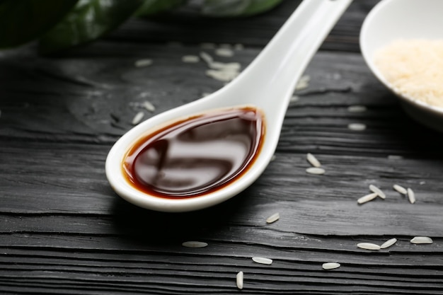 Photo spoon with tasty soy sauce on wooden table closeup