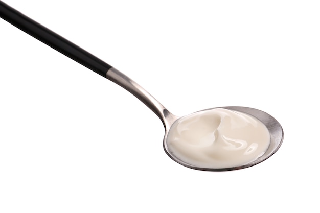 Spoon with tasty yogurt on white