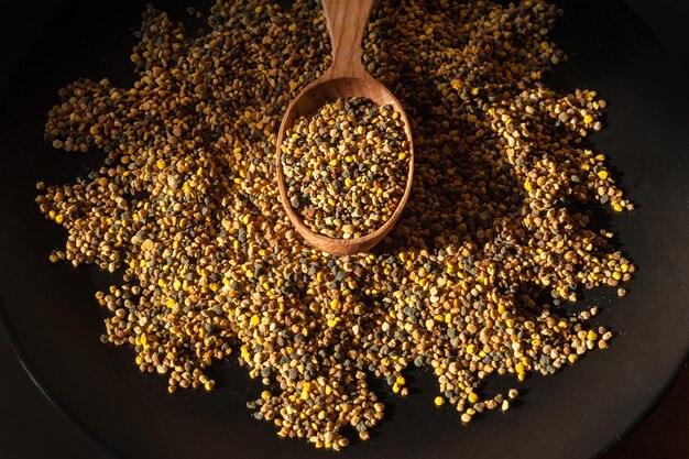 Spoon wooden with closeup of bee pollen on black plate organic medicinal food top view