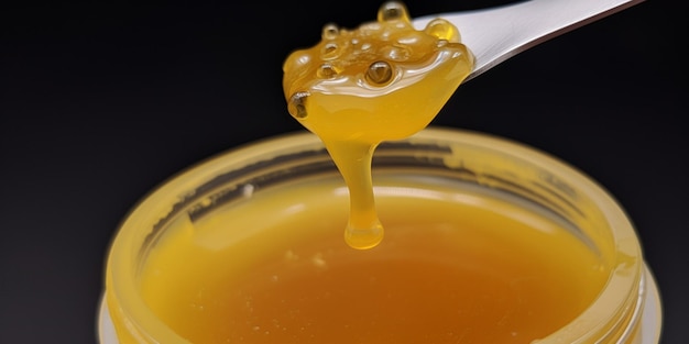 A spoonful of honey hangs from a spoon.