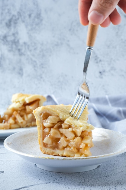 Spooning Slice of apple pie in white plate