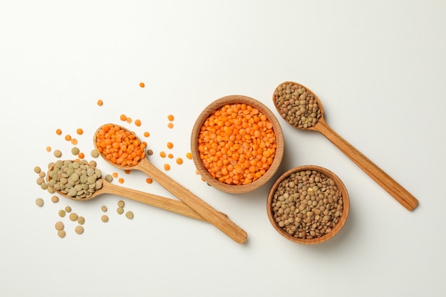 Spoons and bowls with different legumes on white