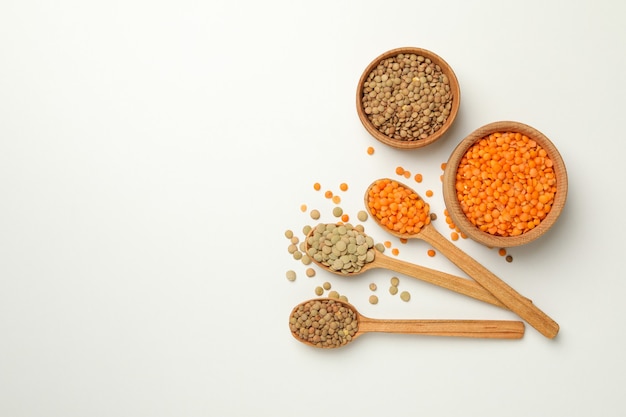 Spoons and bowls with different legumes on white