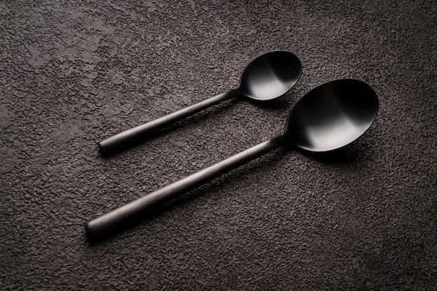 Spoons, teaspoons and regular ones, a couple. They're lying on a dark table. design for a restaurant or coffee shop.