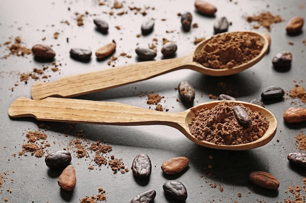 Spoons with aromatic cocoa powder and beans closeup