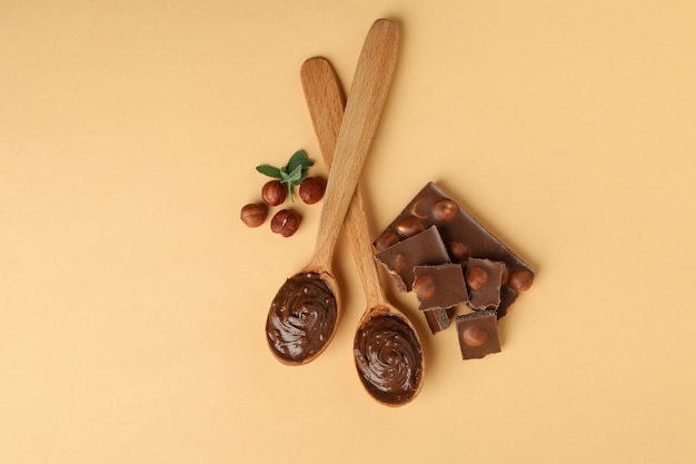 Spoons with chocolate paste, nuts, chocolate and mint on beige background