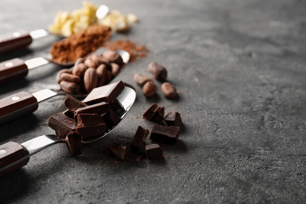 Spoons with different cocoa products on grey background