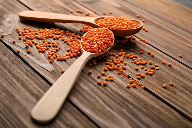 Spoons with healthy lentils on wooden background