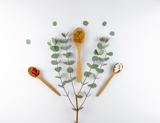 spoons with pills and a branch of eucalyptus