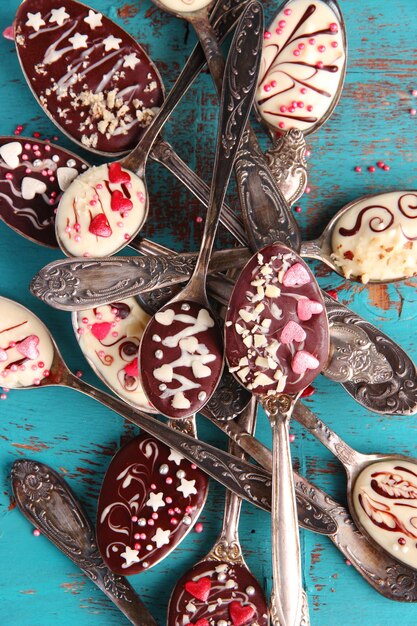 Photo spoons with tasty chocolate for party on old blue wooden table