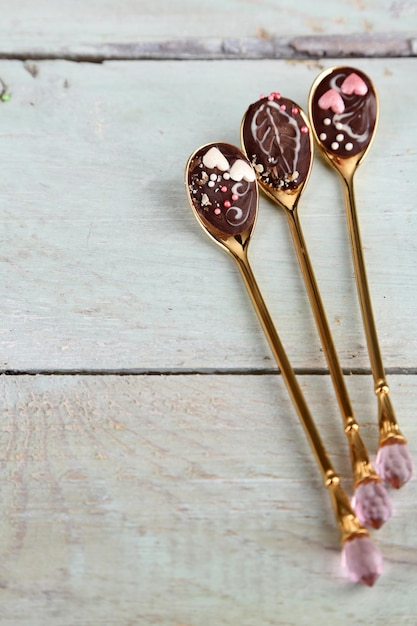 Photo spoons with tasty chocolate for party on old wooden table