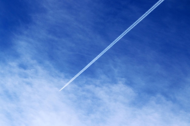 Spoor van het hoogvliegende vliegtuig op de blauwe lucht met witte wolkenxAxA