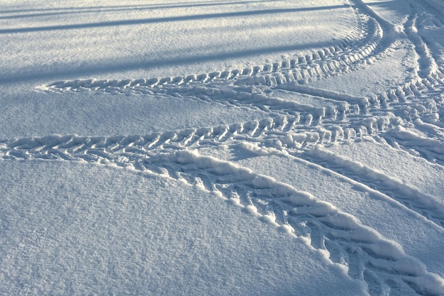 Sporen van een tractor op wielen die ronddraait in diepe sneeuw Winterpatronen en -textuur