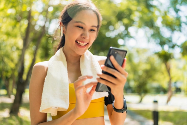 Foto sport attivo femminile asiatico sport panno impostazione smartphone giocando prepararsi per il suo allenamento di routine in esecuzione mattina sano stile di vita sorridente sport donna impostazione percorso di corsa nella sua mappa dell'applicazione