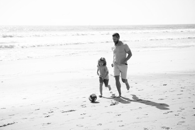 sport activity father and son play soccer or football on beach daddy with kid boy on summer day