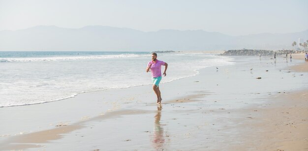 Sport atletische man die op zomerstrand loopt om vrijheid te trainen