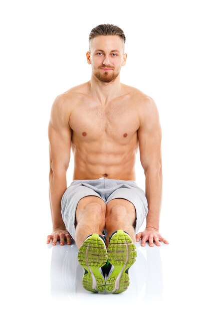 Foto uomo attraente sportivo che fa esercizi di fitness sullo sfondo bianco