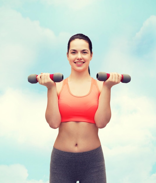 sport-, bewegings- en gezondheidszorgconcept - jonge sportieve vrouw met lichte halters