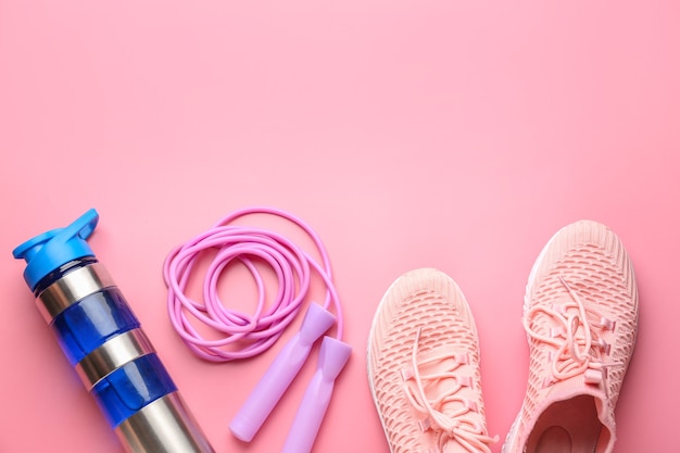 Sport bidon, schoenen en touwtjespringen op roze achtergrond