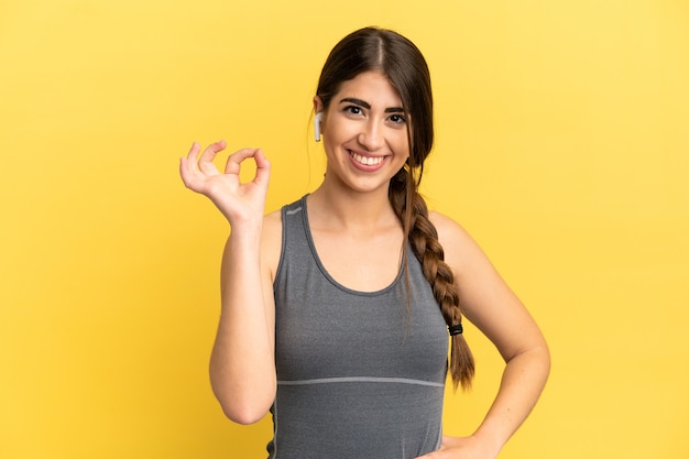 Sport blanke vrouw geïsoleerd op gele achtergrond met ok teken met vingers