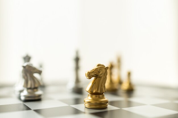 Sport board game, Business and planning concept. Closeup of knight chess piece on chessboard with other pieces.