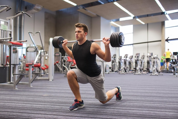 Sport, bodybuilding, levensstijl en mensenconcept - jonge man met barbell die spieren buigt en schouderpers laat vallen in de sportschool