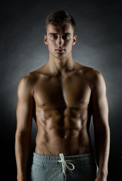 sport, bodybuilding, strength and people concept - young man standing over black background